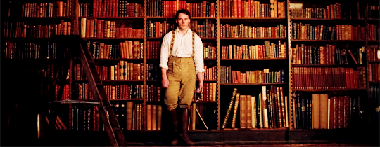 sam claflin standing in front of books in my cousin rachel