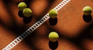 several green tennis balls on a reddish brown surface