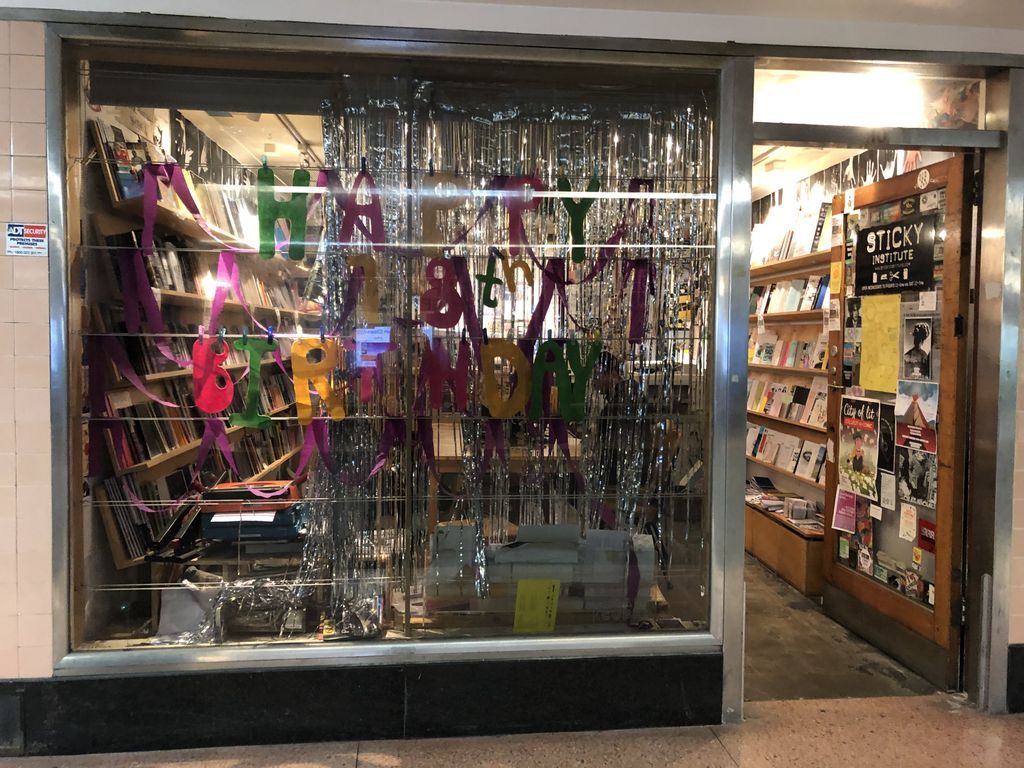 Shop window filled with tinsel, door open revealing bookshelves filled with zines