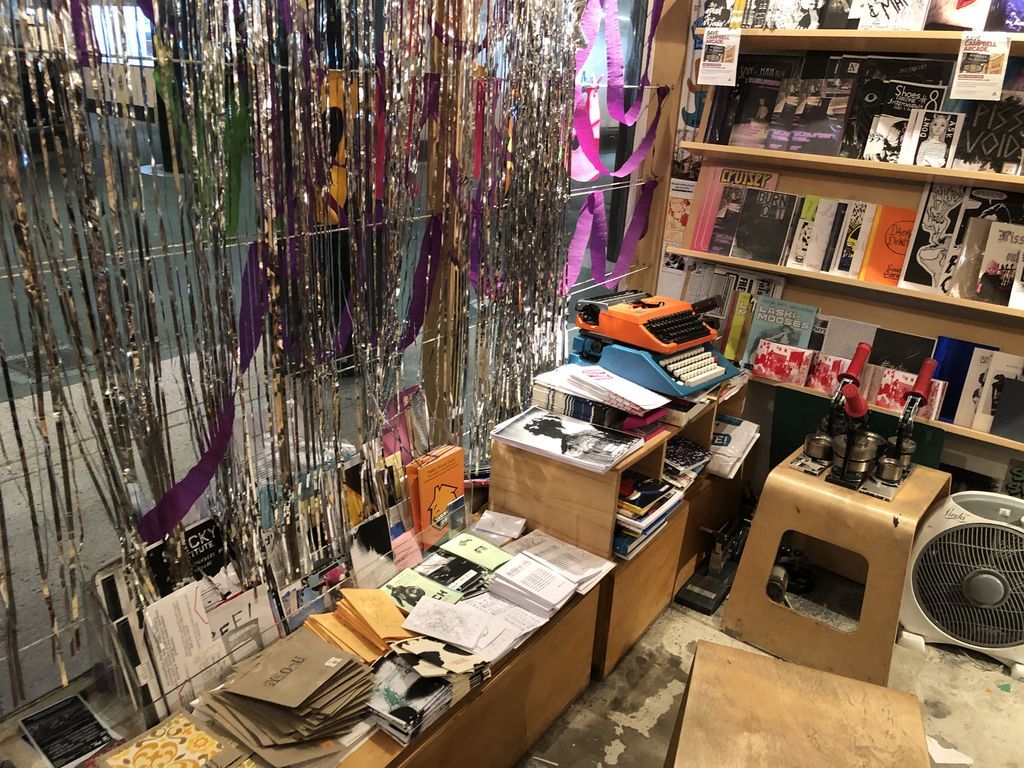 Shop floor and shelves, with typewriters, stools and zines