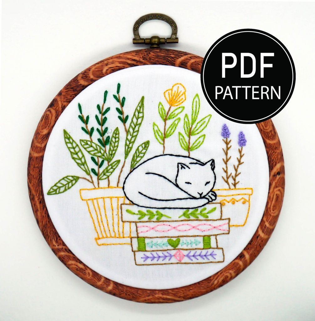 Embroidery of a cat sleeping on a pile of books, surrounded by potted plants