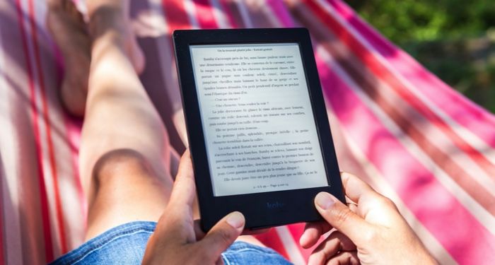 person in a striped hammock reading a story on a Kindle