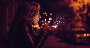 woman blowing sprinkle confetti in the air from cupped hands