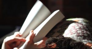 image of hands holding a book while resting on a blanket https://unsplash.com/photos/xZiHAa09Jcs