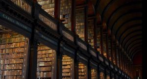 low-angle photograph of stacks in an old library with dark wood and an arched ceiling