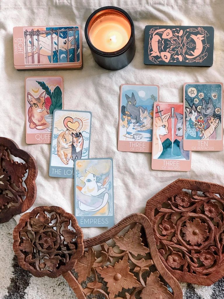 Images of cards from the Tarot Cat deck arranged with a candle