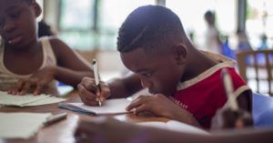 child writing on paper in a notebook in a school setting