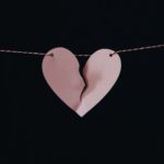 a pink paper broken heart hanging on a string