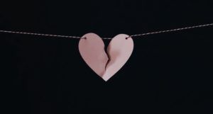 a pink paper broken heart hanging on a string