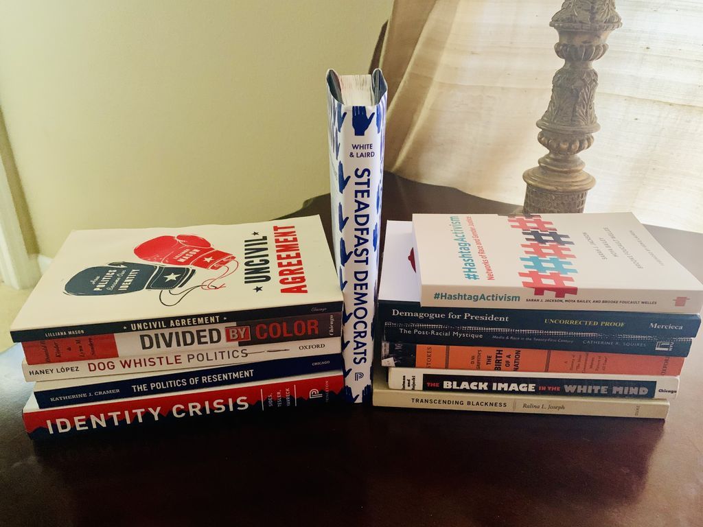 Stacks of books. Poli Sci: Identity Crisis, The Politics of Resentment, Dog Whistle Politics, Divided by Color, Uncivil Agreement, and Steadfast Democrats. Communication and Cultural Studies: Hashtag Activism, Demagogue for President, The Post-Racial Mystique, D.W. Griffith’s The Birth of a Nation, The Black Image in the White Mind , and Transcending Blackness.