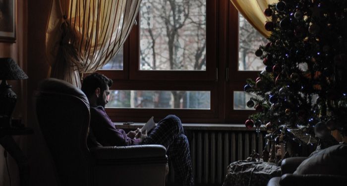 man reading next to the christmas tree in winter