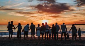 big family gathered on the beach watching the sunset