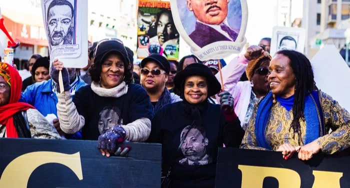 Black women holding Martin Luther King Jr signs at march for civil rights and Black history feature