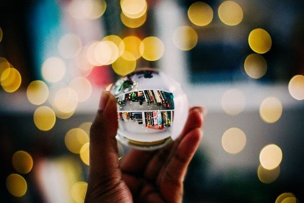 Person holding clear crystal ball in front of bookshelves