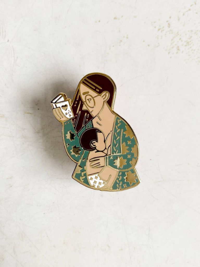 Enamel pin of a breastfeeding woman reading