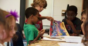 children in a classroom looking at a book in school