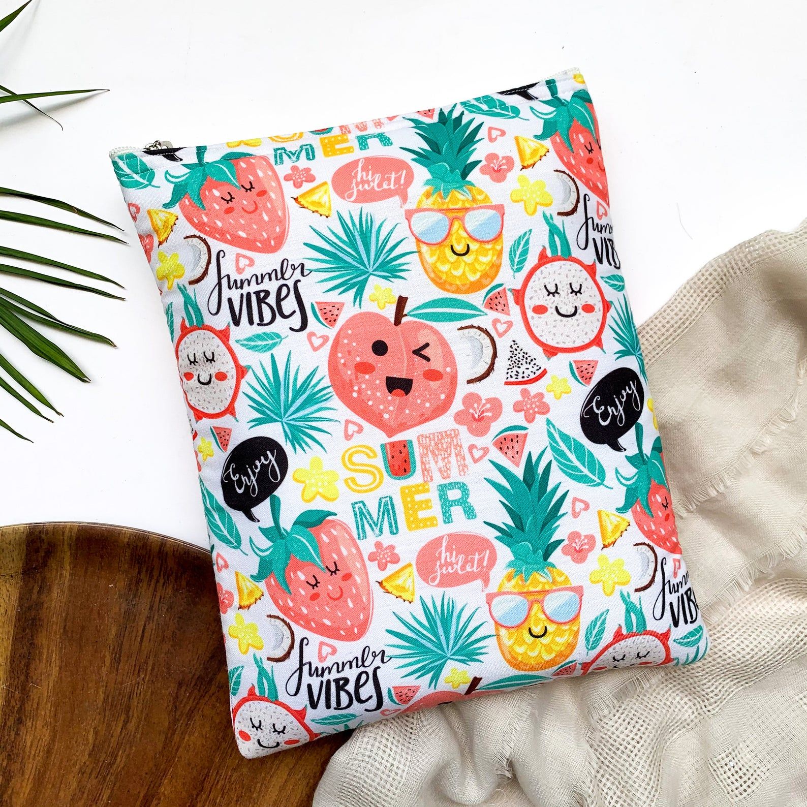 A colourful book sleeve with a white background and a pattern of fruits with happy facial expressions (strawberries, pineapples, watermelonds, etc). 