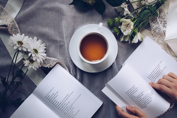 Photo of open poetry books with tea and flowers