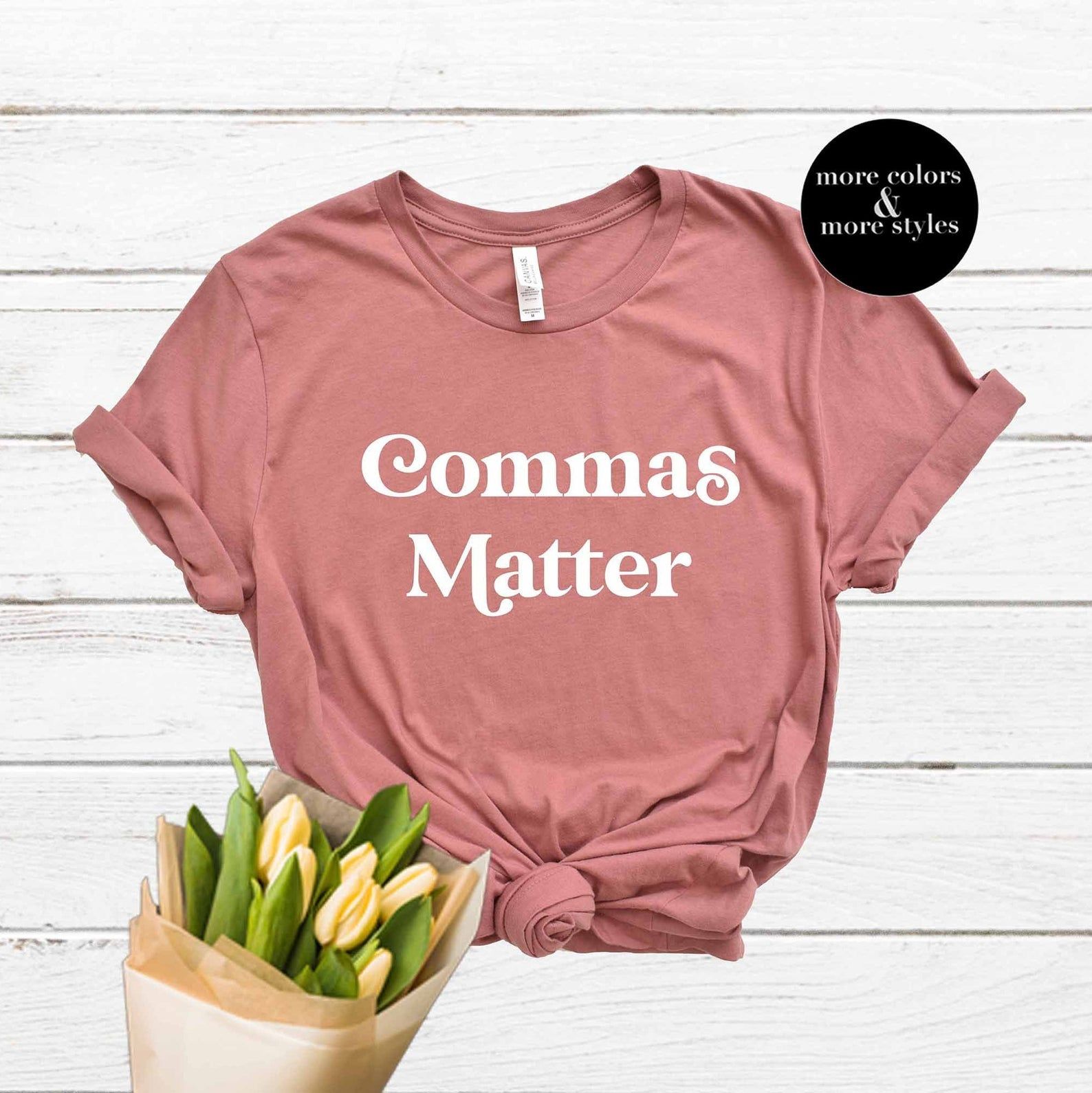 A pink shirt that says "Commas matter". The small black text box reads "more colors & more styles," and there is a bouquet of flowers at the bottom of the photo.