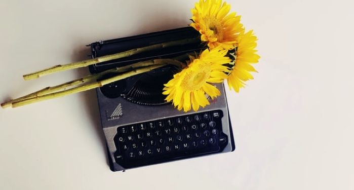 black typewriter with yellow flowers on top