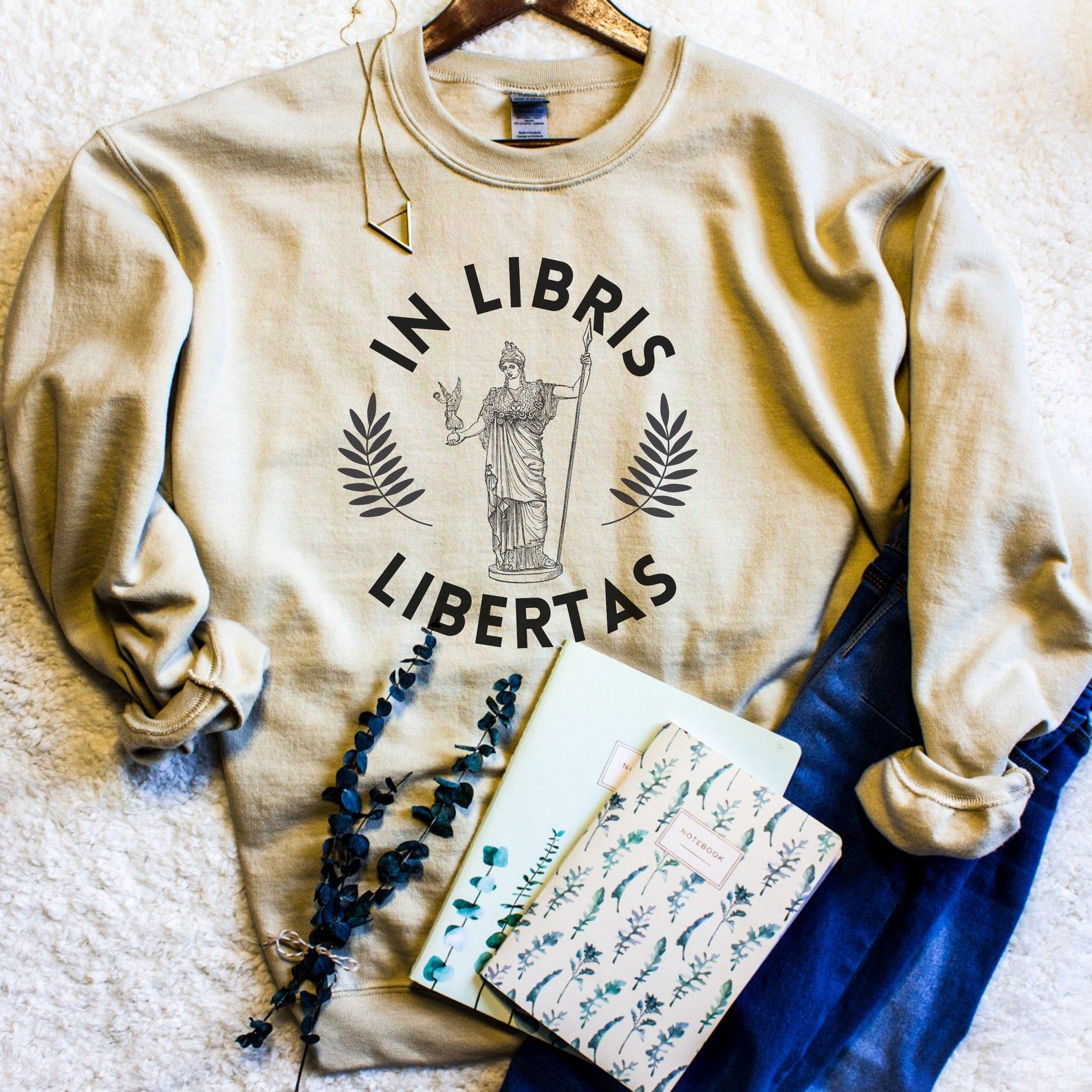 Image of a cream sweatshirt reading "In Libris Libertas." 