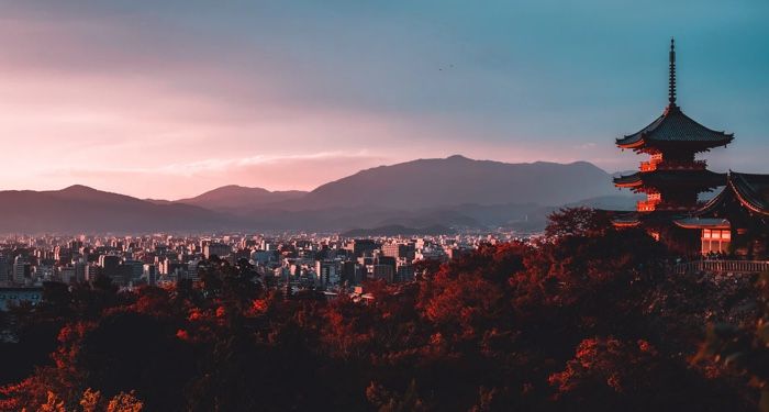 a pagoda surrounded by trees with mountains in the background in Japan https://unsplash.com/photos/E_eWwM29wfU