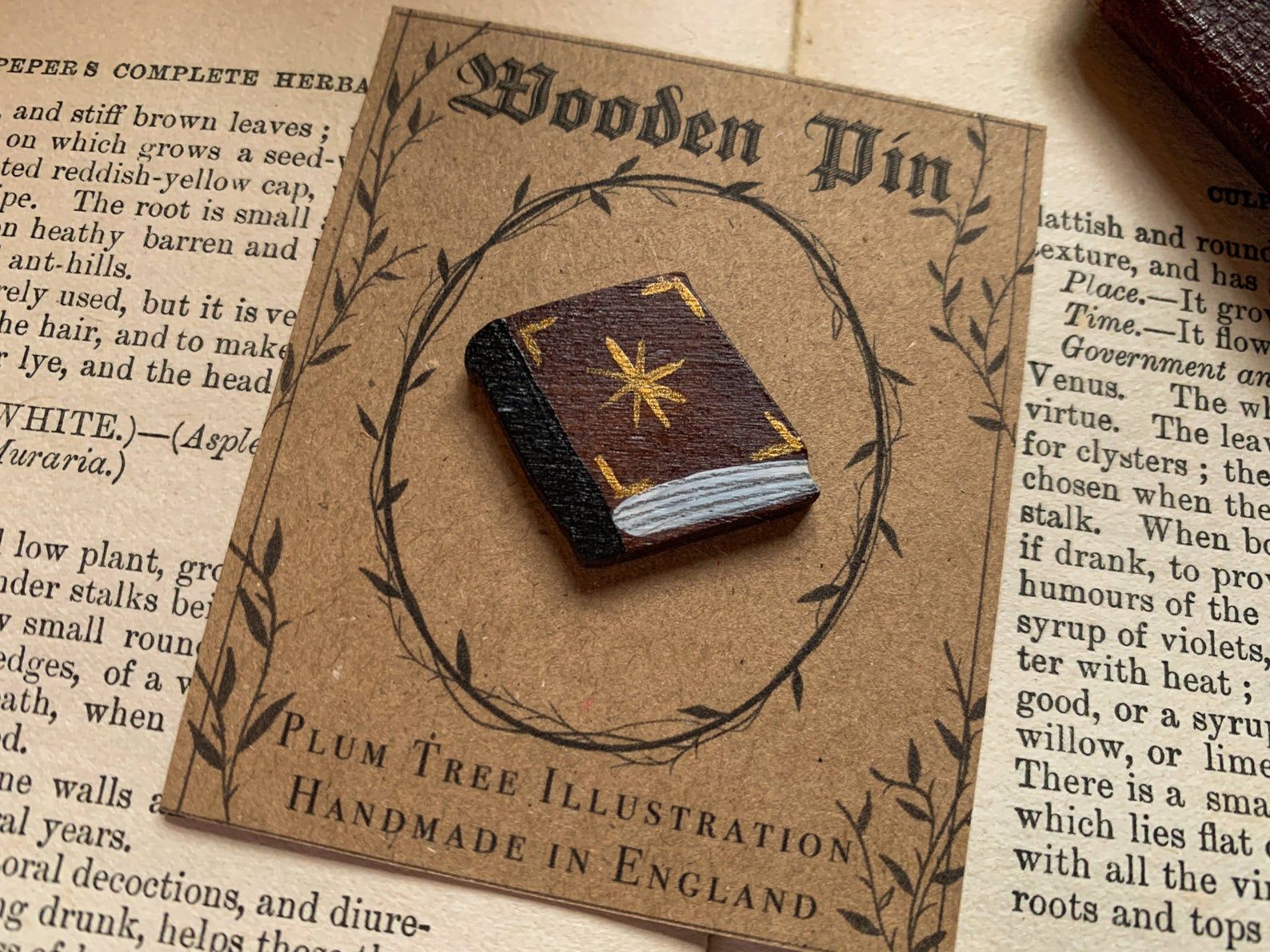 Image of brown wooden pin in the shape of a book. 