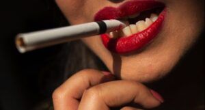 closeup of a woman with a cigarette purse between red lipsticked elips