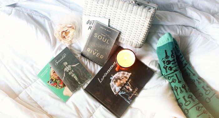 Image of poetry books on a sheet with green socked feet beside them.