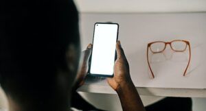 Image of the back of a Black man's head as he uses a cell phone