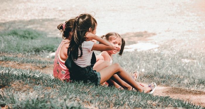 Image of three kids sitting in the grass