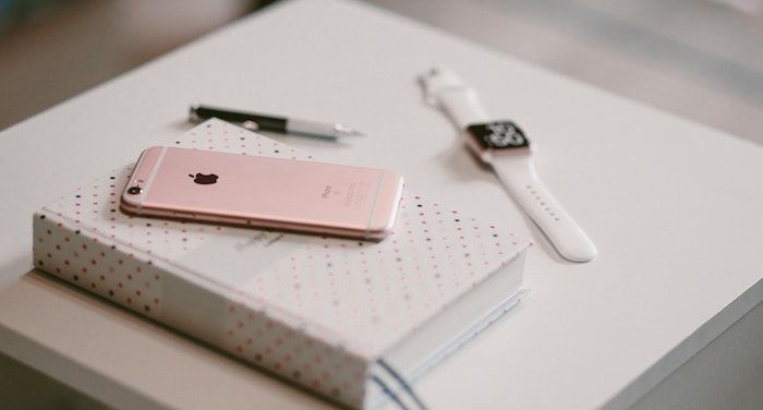 Image of a phone, book, and watch on a white table