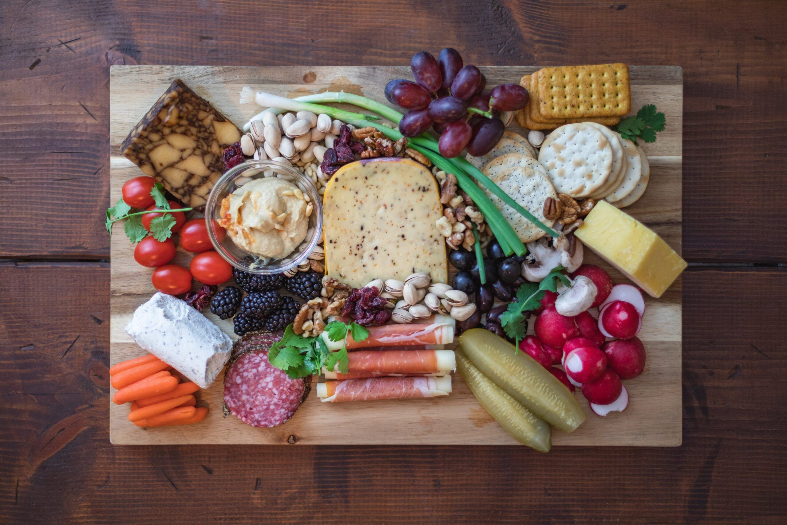 cheese, meat, fruit, and vegetables on cutting board