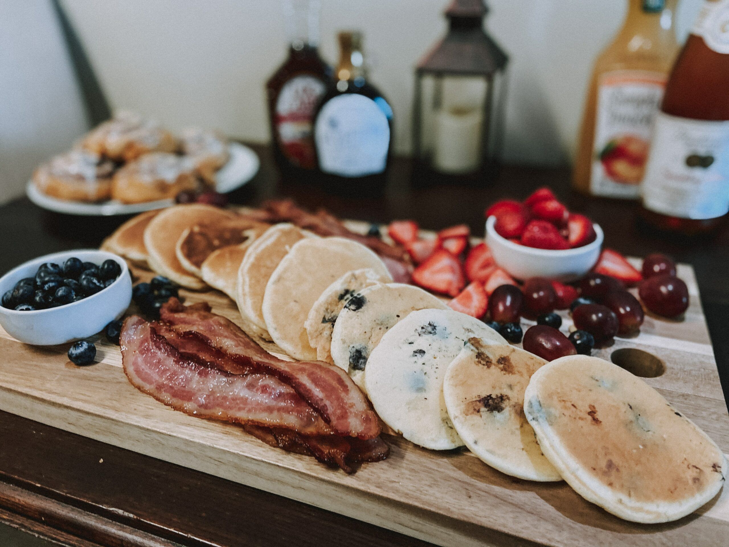 pancakes and bacon on cutting board with fruit