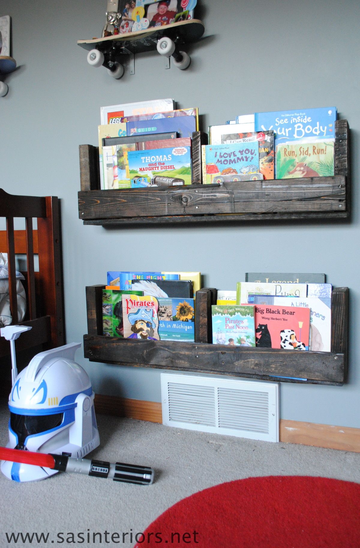 two pallet wooden bookshelves hanging on a wall with children's books inside