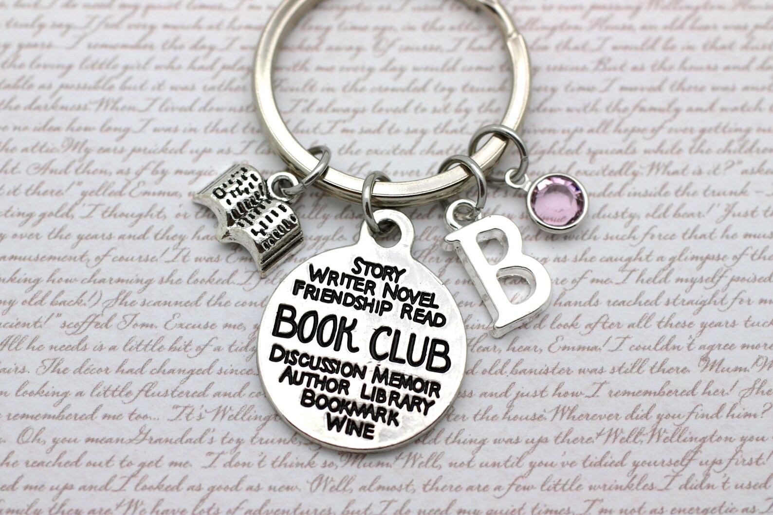charm bracelet with a birthstone, an initial, a mini book, and a circle with many bookish words, and the word "book club" bigger in the centre