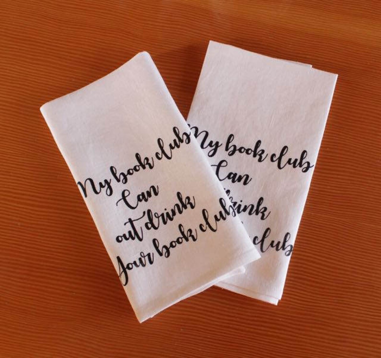 White tea towels with the words "my book club can outdrink your book club"