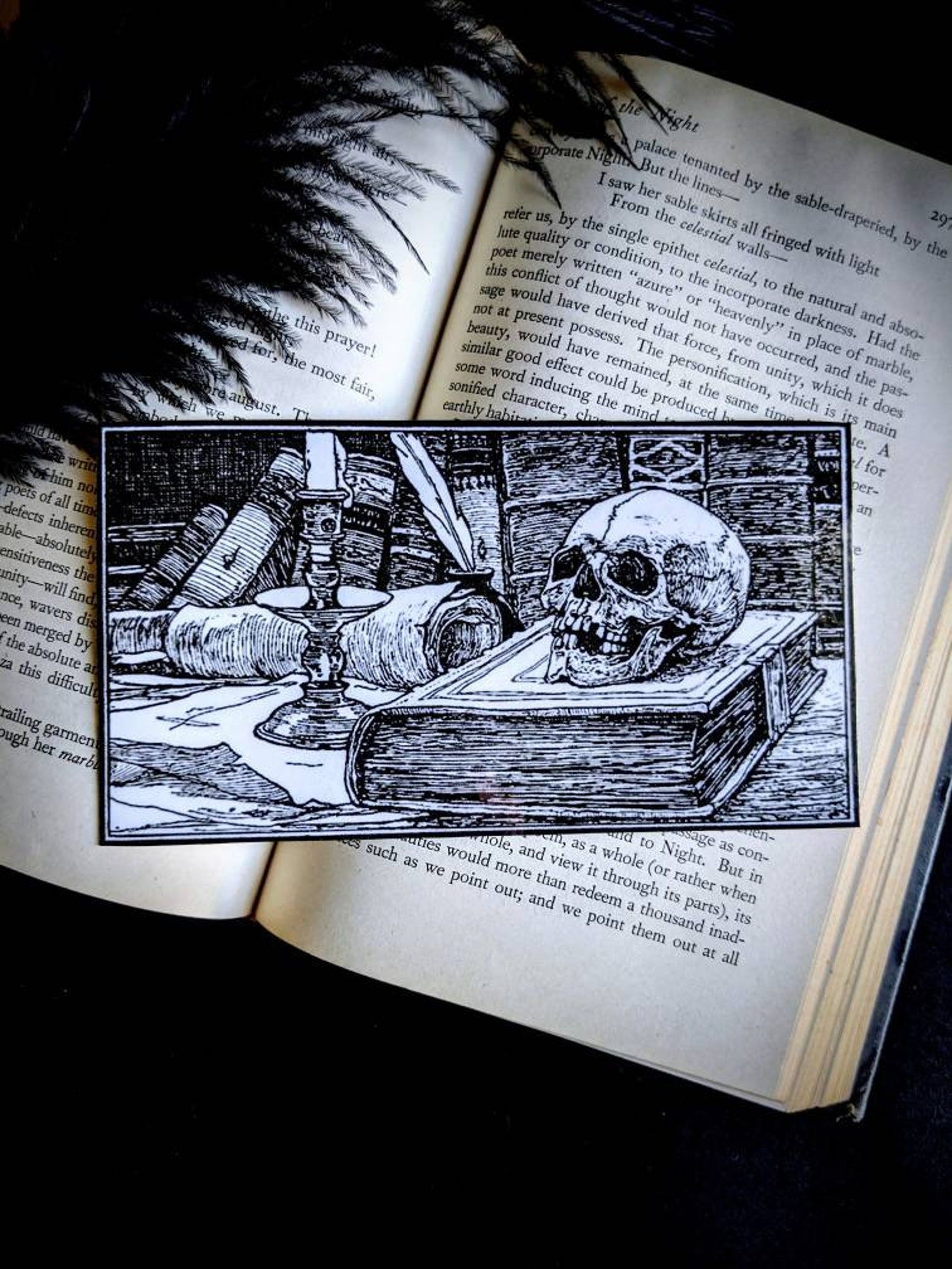 a black and white drawing of a book on a table with a skull, quill pen, manuscripts, and a candle