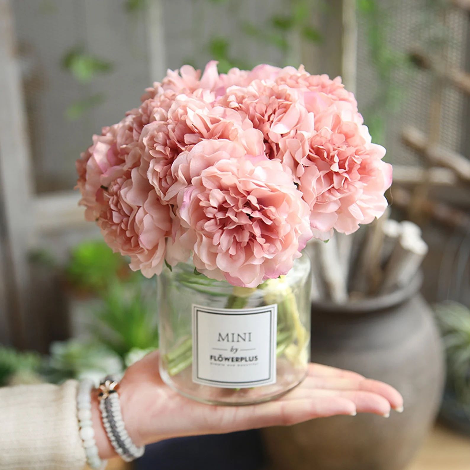 Photo of pink, artificial silk peony blooms in a glass vase.