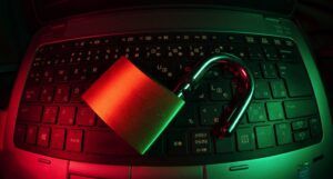 a padlock resting on a laptop keyboard, image is bathed in red and green light