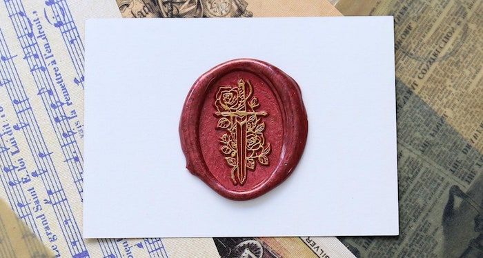 red wax stamp featuring a sword and roses