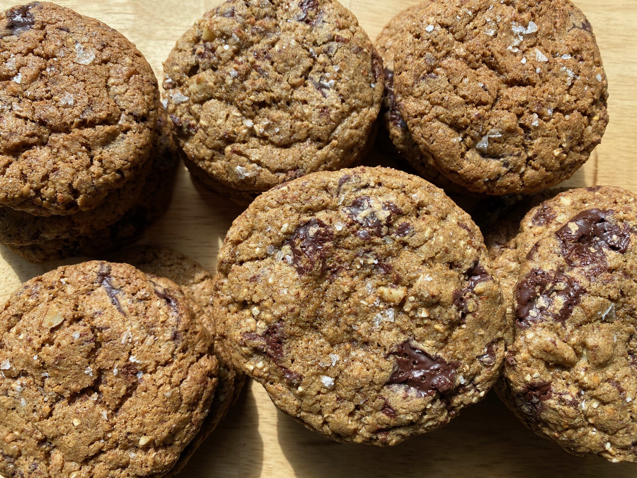 Stacks of large, crinkly chocolate chip cookies, toped with flaky salt, big chunks of mealy chocolate visible. Photo taken by me.