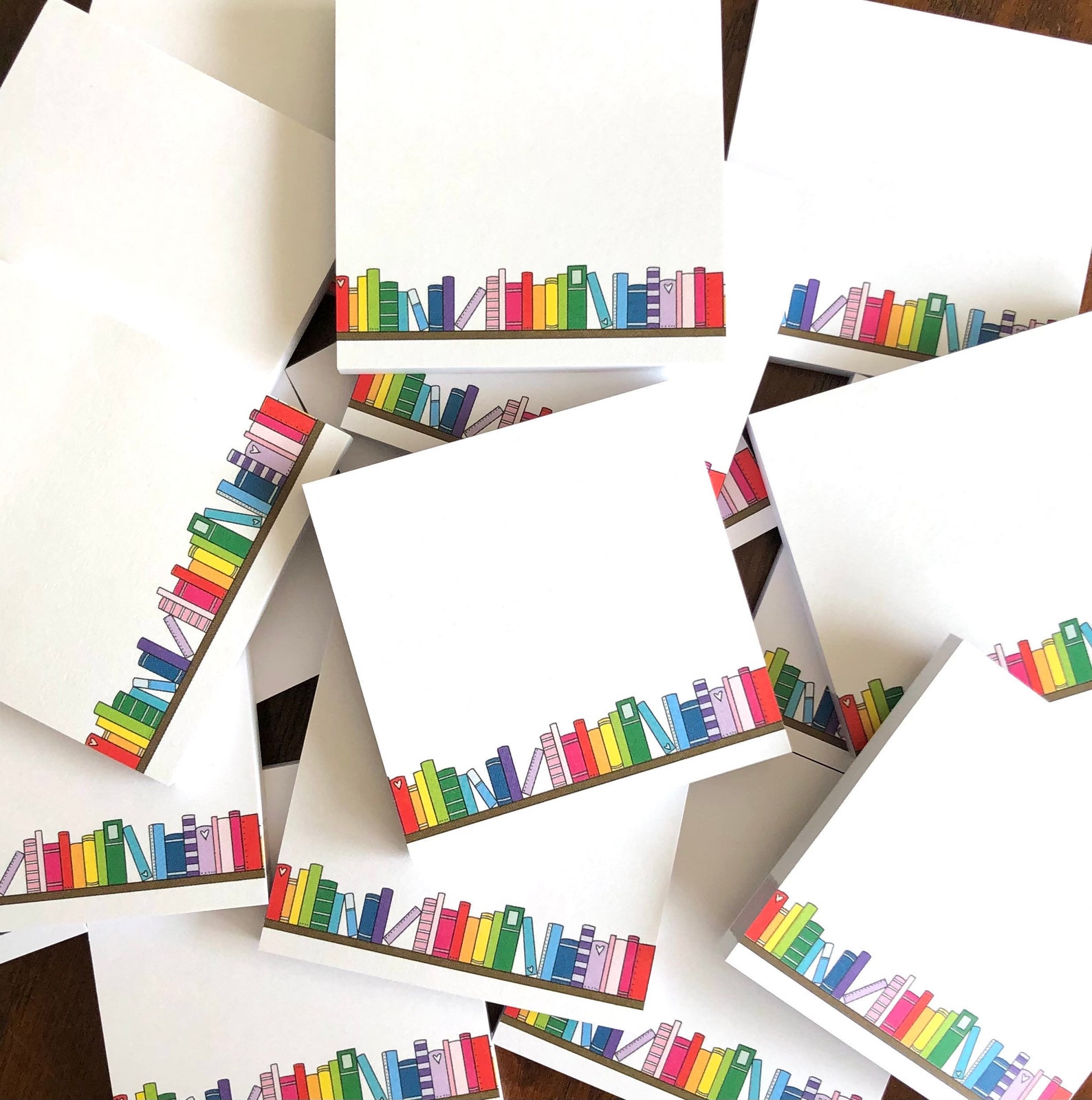 A stack of sticky notes with a rainbow of books on a shelf along the bottom of the notes.