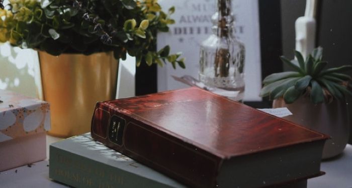 books stacked in front of a couple plates on a desk