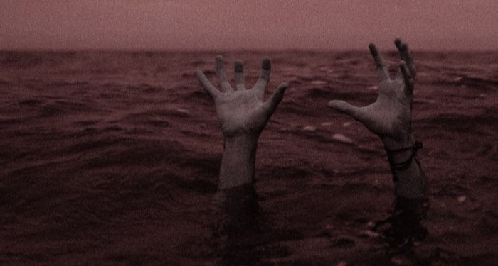 the hands of a drowning person coming out of a body of water