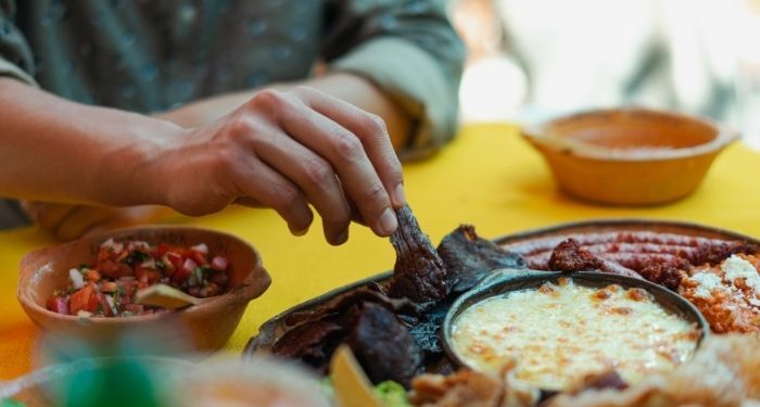 image of a brown hand pulling food from a shared plate