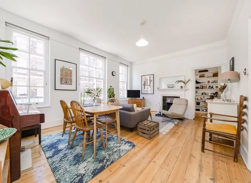 Image from apartment listing of the spacious living room, including original wood floors.