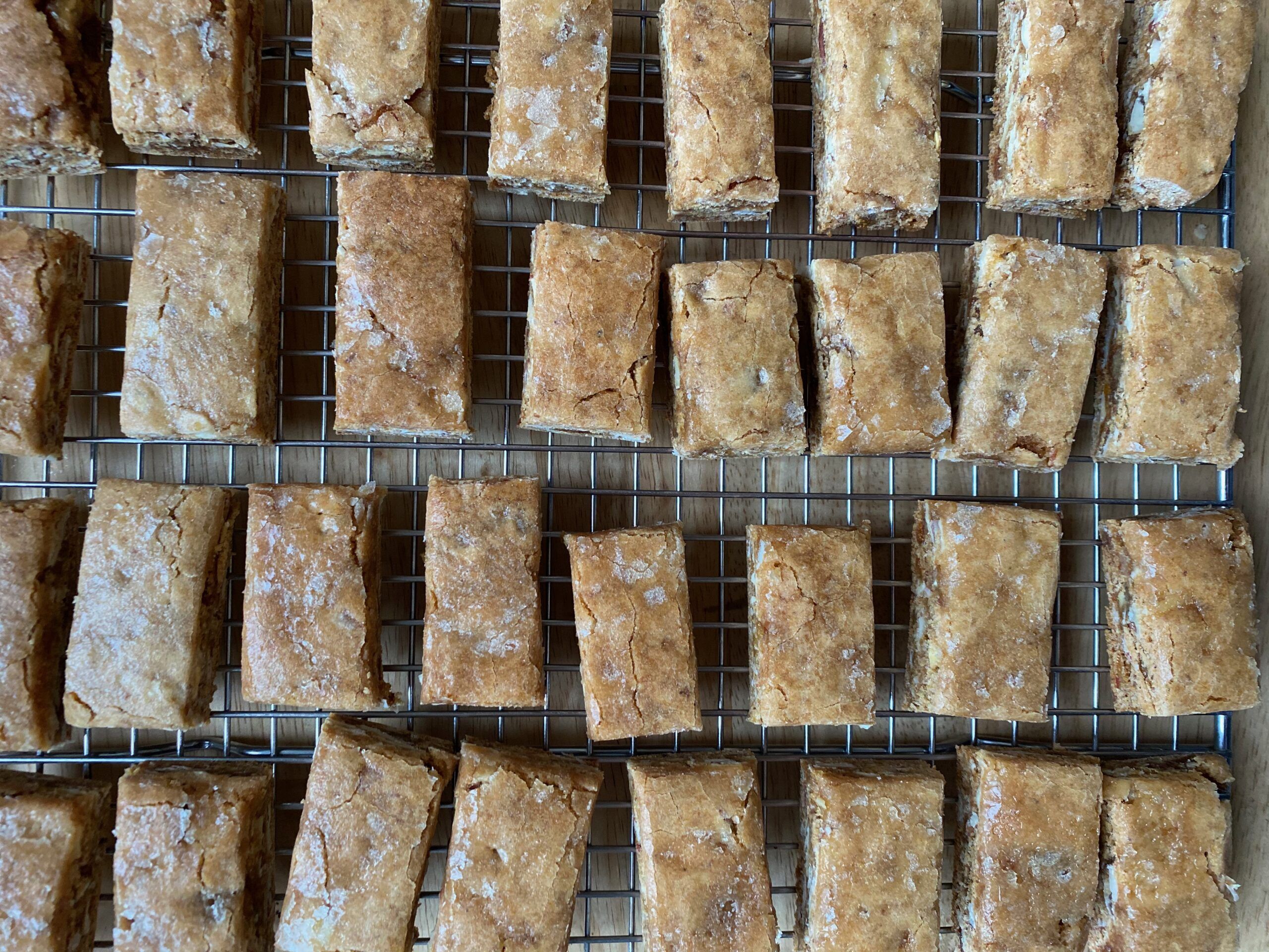 A metal cooling tray full of small rectangular leckerli bars, with a shiny crackly glaze on top.