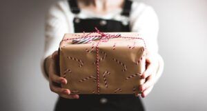 a photo of a figure presenting a candy cane patterned present