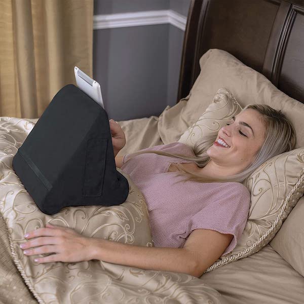 Woman lying in bed with a black fabric-covered tablet holder sitting on her stomach